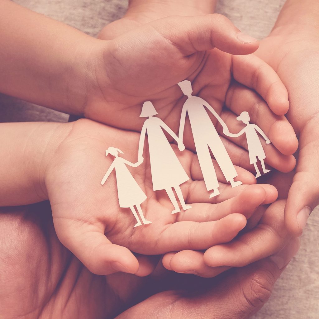 Adult and children hands holding paper family cutout, family home, foster care, homeless support concept